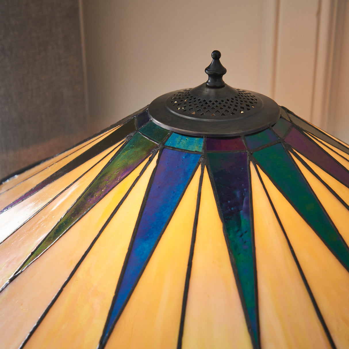 Close-up of Tiffany stained glass dark star pattern lamp shade with metal finial