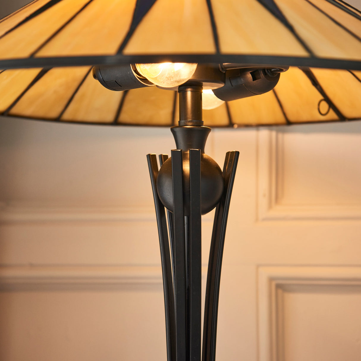 Dark metal Tiffany-style starburst table lamp with yellow stained glass shade indoors