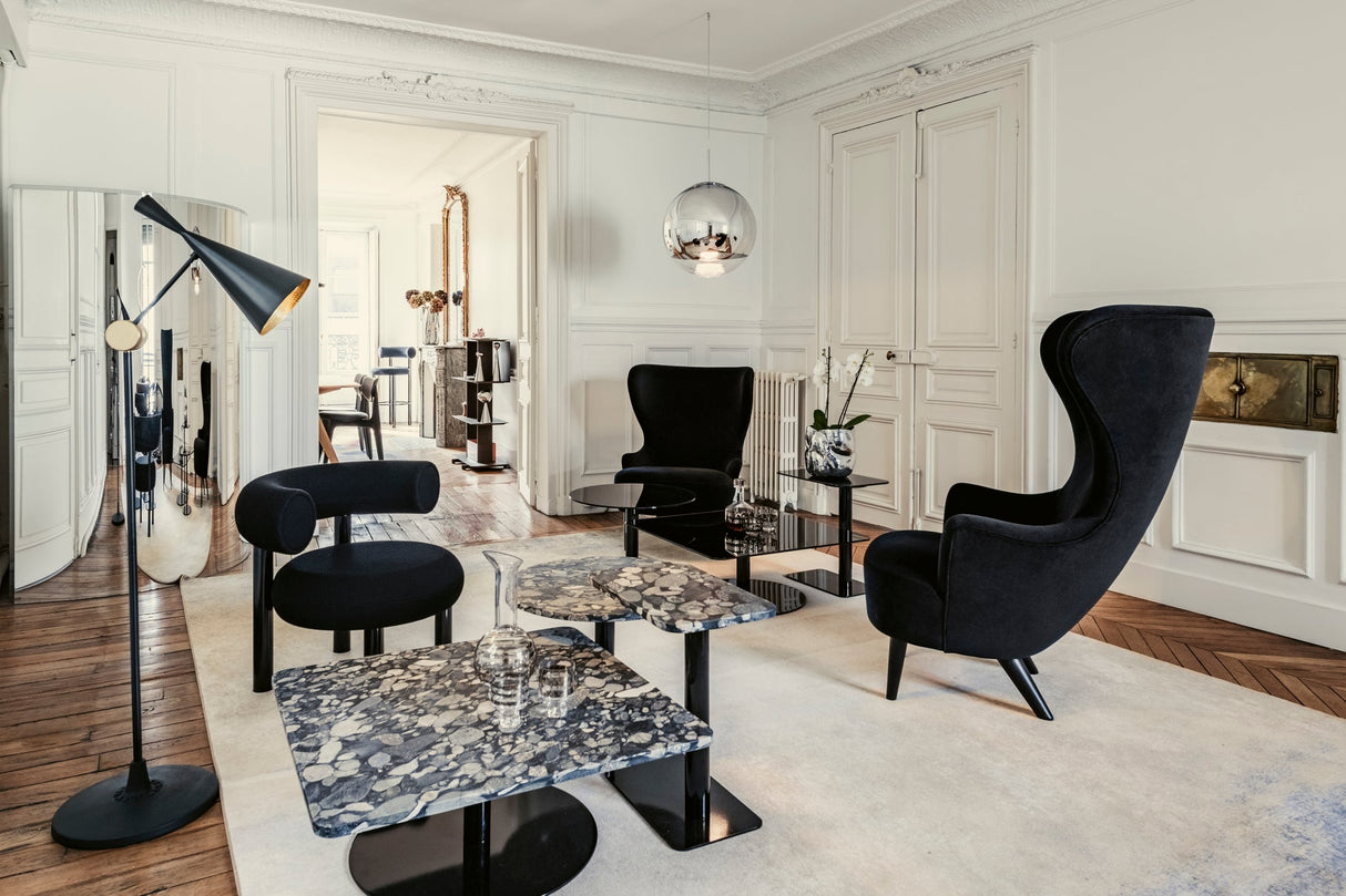 Modern living room with black wingback and curved chairs, terrazzo coffee tables, floor lamp, and pendant light