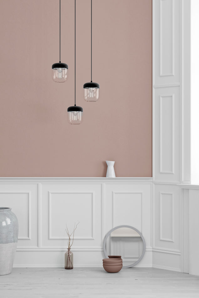 Modern interior with three black pendant lights, pink wall, white paneled trim, decorative vases, and round mirror
