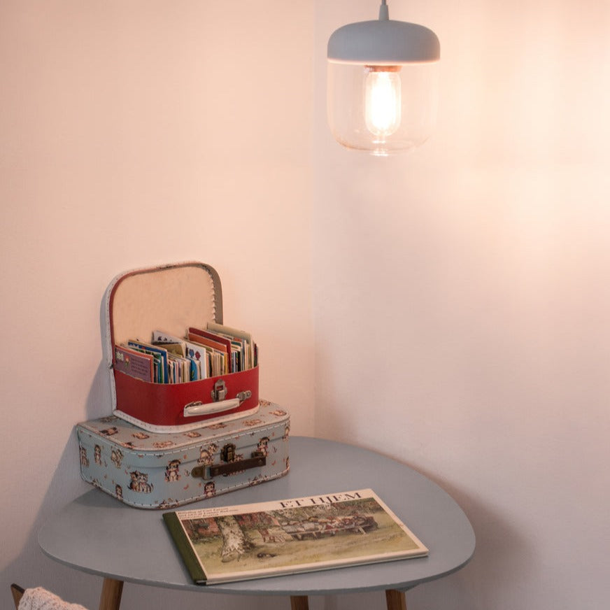 Cozy corner with vintage suitcases holding books on a small table under a warm hanging pendant light