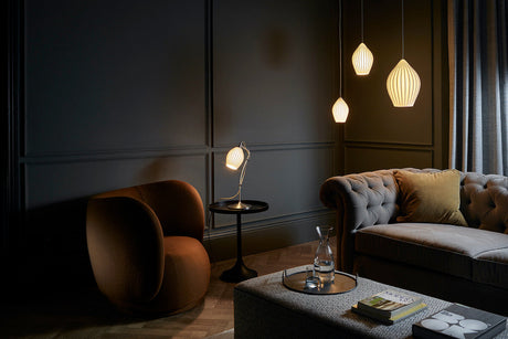 Cozy modern living room with gray tufted sofa, brown curved chair, pendant lights, and wooden flooring