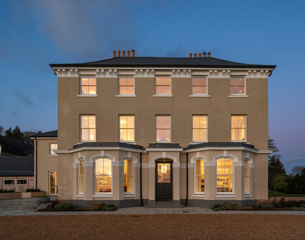 Elegant manor house at dusk with warm illuminated windows and classic architecture