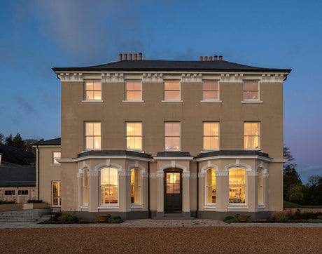 Elegant manor house at dusk with warm illuminated windows and classic architecture
