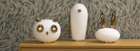 Amos Lighting animal lamps featuring white glass with gold accents on owl, bird, and bunny designs on wooden surface