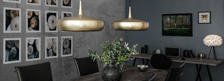 Modern dining room with black chairs, wooden table, pendant lights, botanical centerpiece, and nature wall art