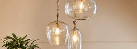 Amos lighting pendant cluster with three clear glass bulbs and warm Edison lights in a beige room