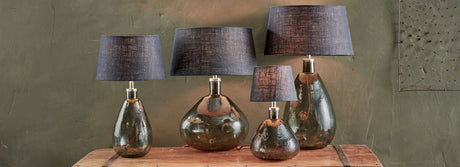 Set of four modern glass table lamps with dark linen shades on rustic wooden table