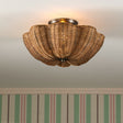 Wicker ceiling light fixture above a framed picture with striped wallpaper.