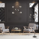 Modern living room with gray armchairs, gold coffee table, decorative lighting, and dark paneled walls