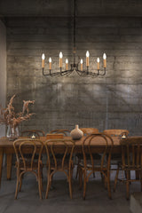 Rustic dining room with wooden table, mismatched wooden chairs, modern chandelier, and dried foliage