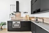 Modern kitchen with black cabinets, concrete countertop, wooden backsplash, and hanging plants