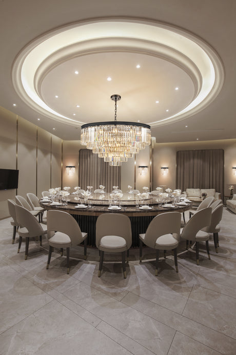 Luxury dining room with round marble table, beige chairs, crystal chandelier, and elegant decor