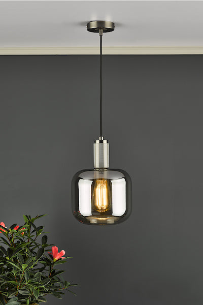 Antique chrome pendant light with smoked glass shade hanging against dark gray wall and green plant