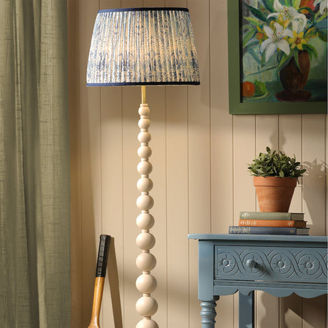 Decorative floor lamp with a unique design in a room setting with a table, plant, and sports equipment.