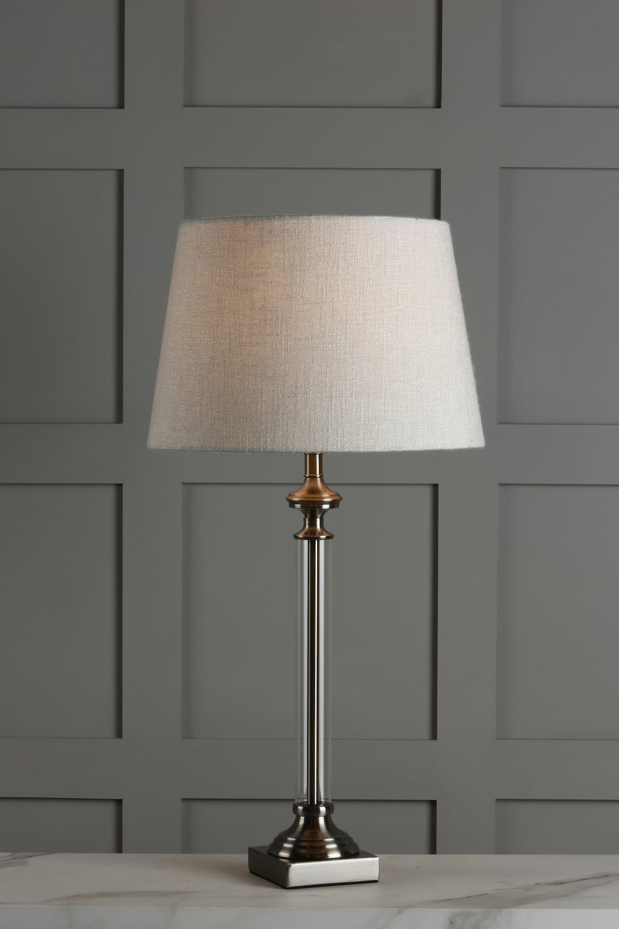 Modern table lamp with white fabric shade and clear acrylic base on marble surface