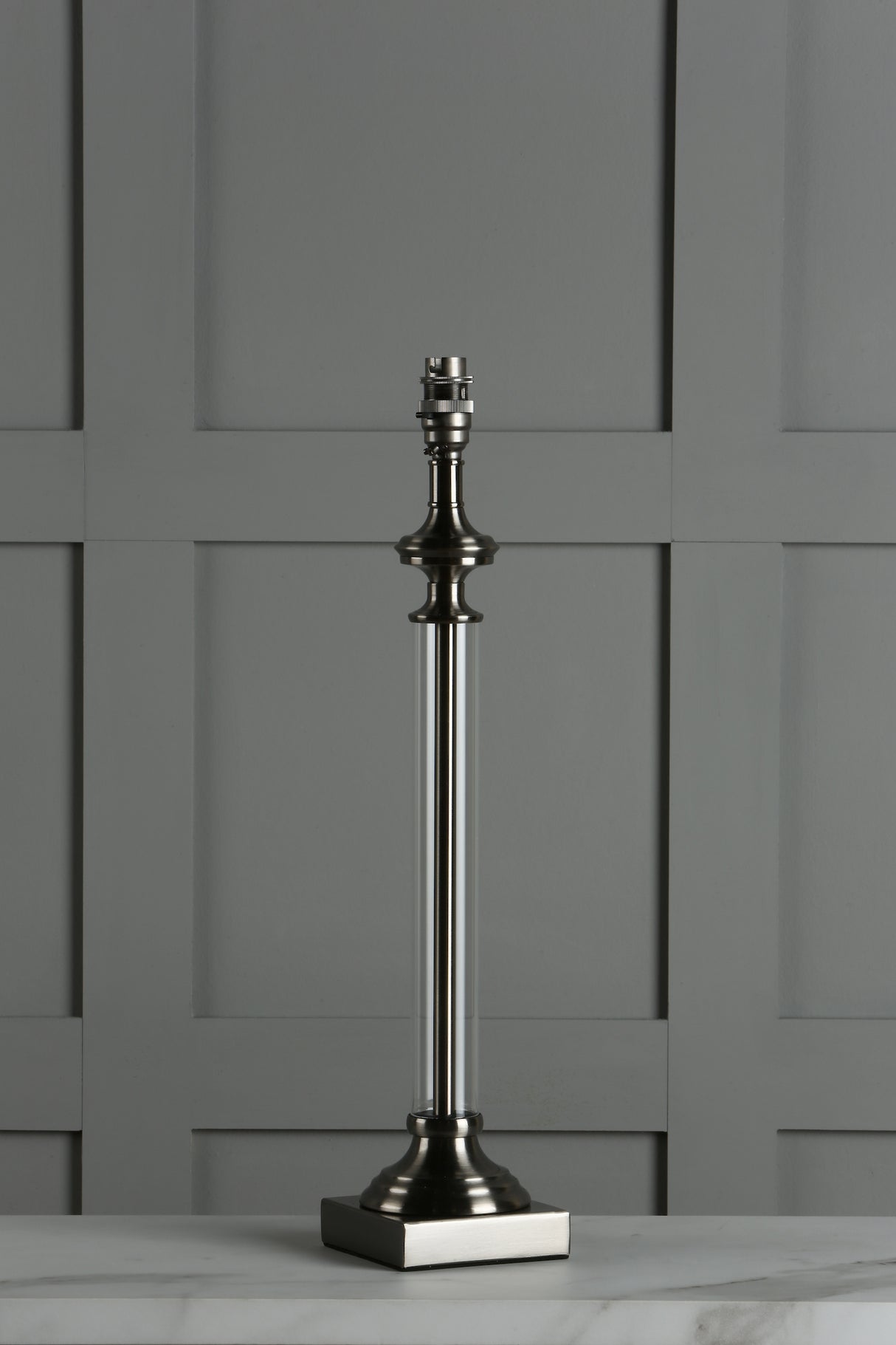 Modern metallic table lamp base with clear cylindrical body on marble surface