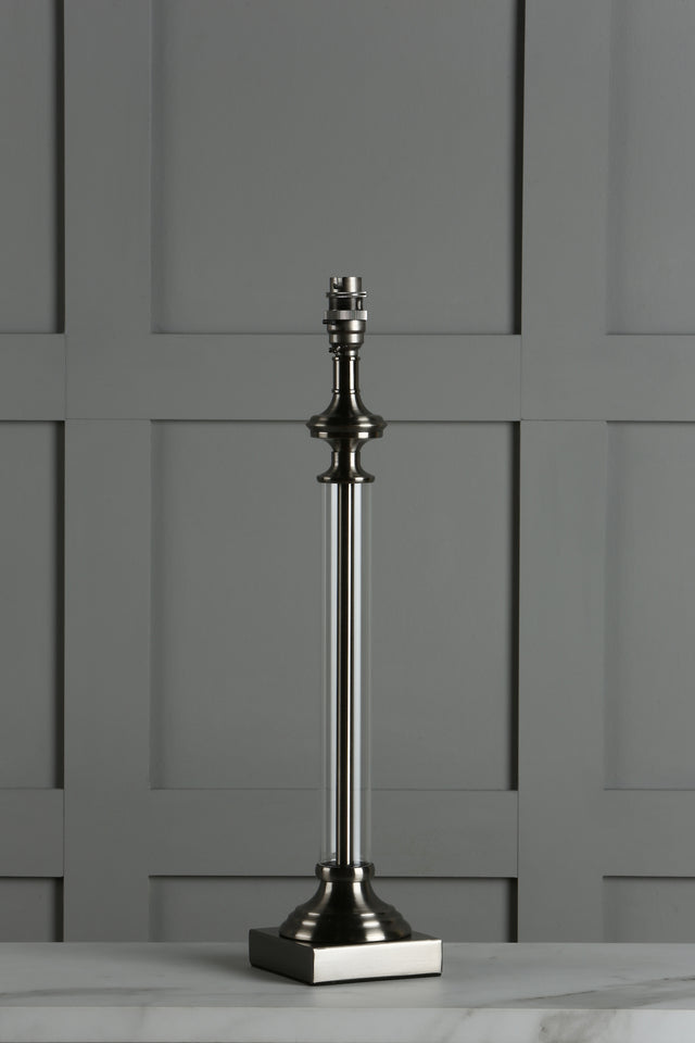 Modern metallic table lamp base with clear cylindrical body on marble surface