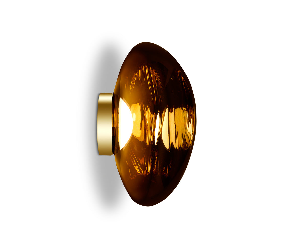 Modern amber glass LED wall light with gold base against white background