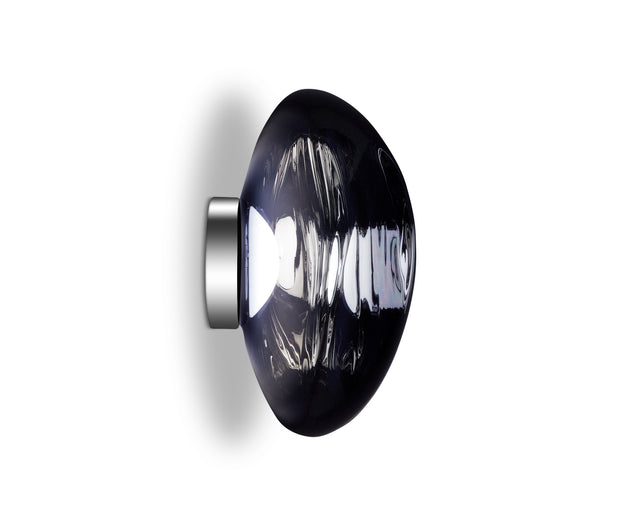 Side view of a modern wall sconce with a smoky glass shade and metallic base on white background