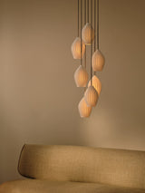 Modern white pendant lights with soft warm glow over beige fabric sofa in minimalist room
