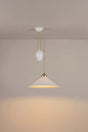 Original BTC Cobb Rise and Fall. Modern pendant light with a beige shade and gold fixture on a plain wall.