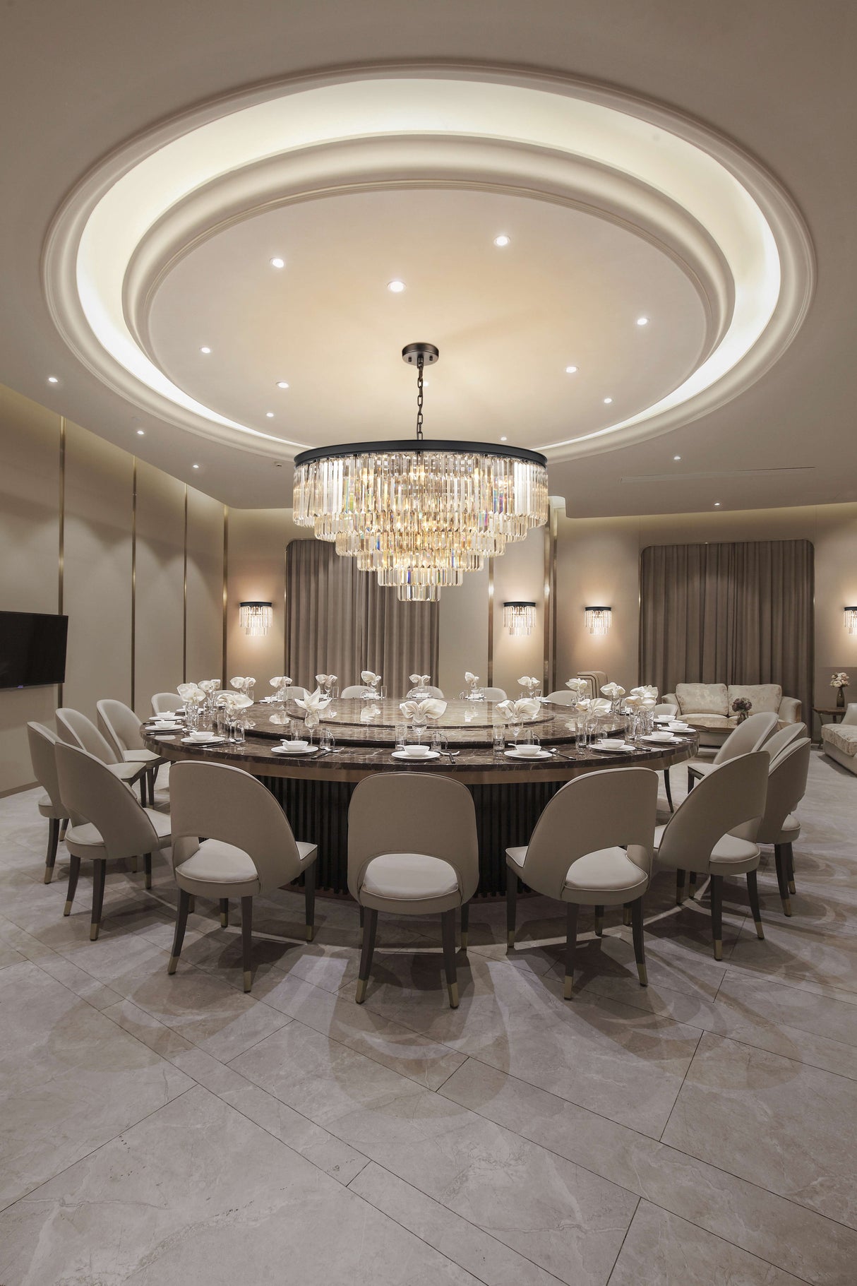 Luxury conference room with large round marble table, beige chairs, crystal chandelier, and soft lighting