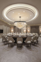 Luxury conference room with large round marble table, beige chairs, crystal chandelier, and soft lighting