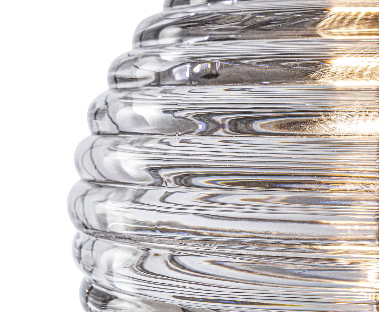 Close-up of a clear ribbed glass pendant light with warm 2700K LED glow