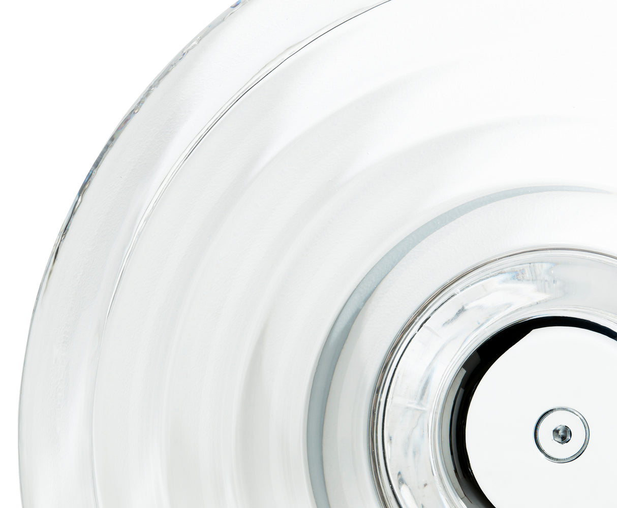 Close-up of a clear glass plate with concentric circular ridges and a central metal screw detail