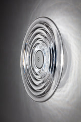 Modern circular glass ceiling light fixture casting patterned reflections on white ceiling