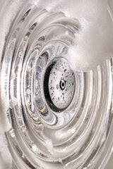 Close-up of clear glass with water droplets and soap foam, highlighting concentric circular patterns